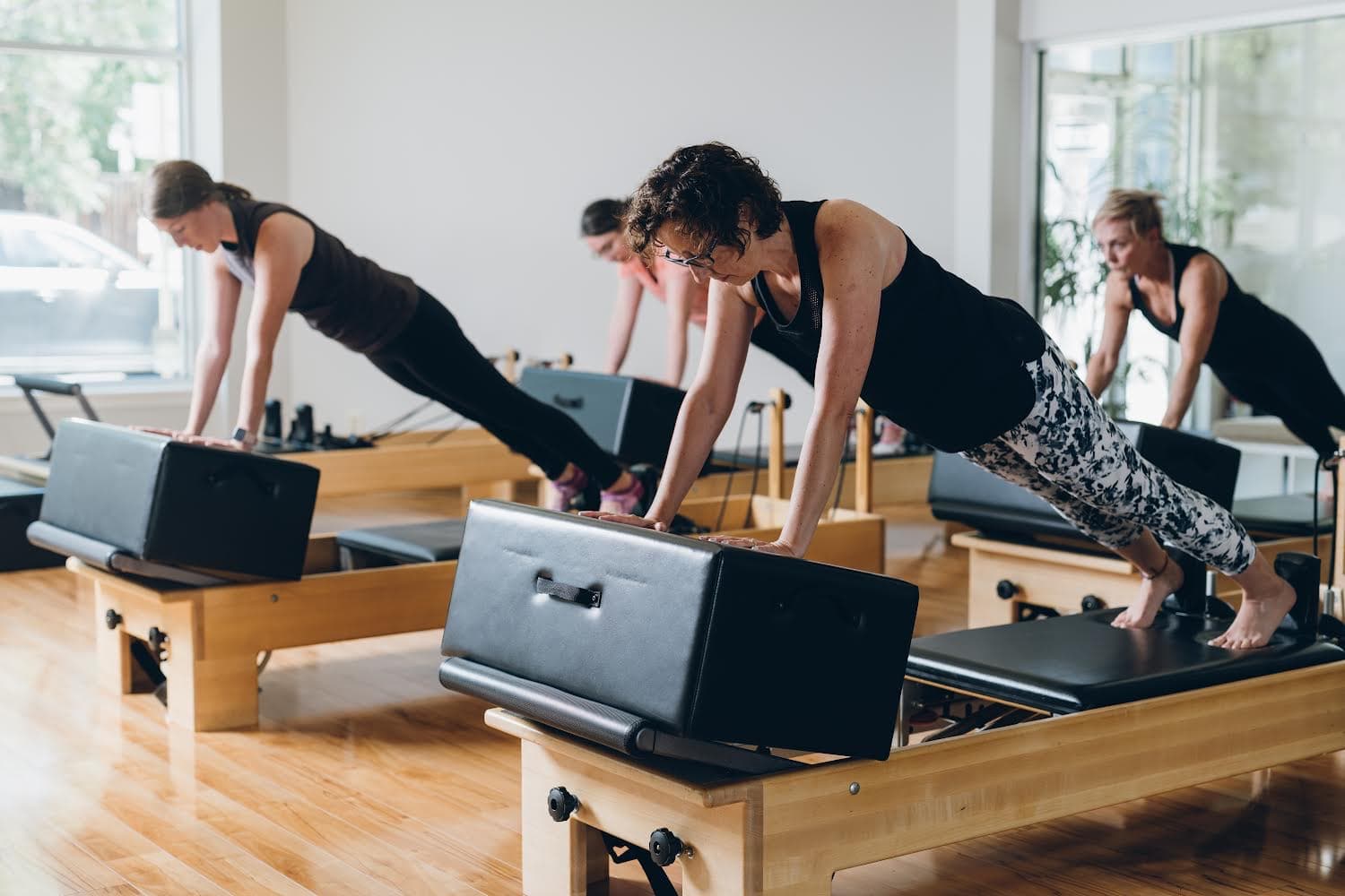 Three women holding a plank on reformer boxes in the main studio